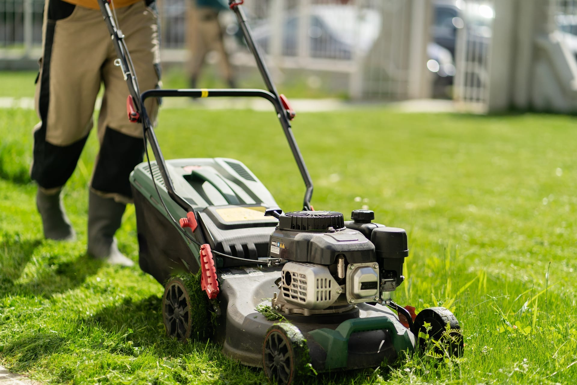 Horticulturist pushing a mower across a green lawn